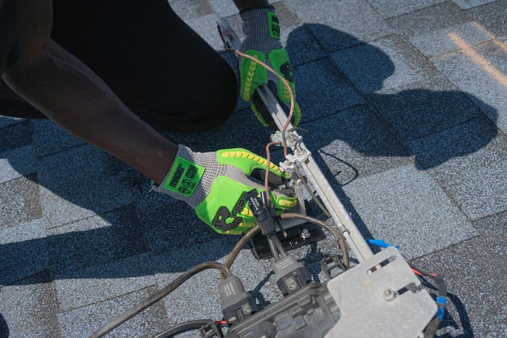 Certified electrician performing hands-on wiring work on a rooftop electrical installation.